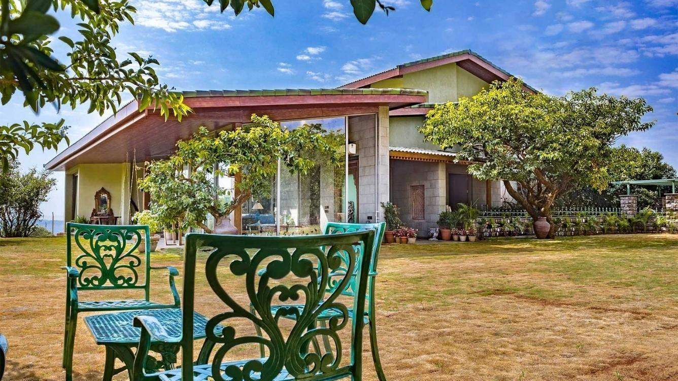 Outdoor view of a Ramsukh Resort villa with lush greenery and decorative furniture.